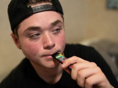 A teenager vaping marijuana from a wax pen.